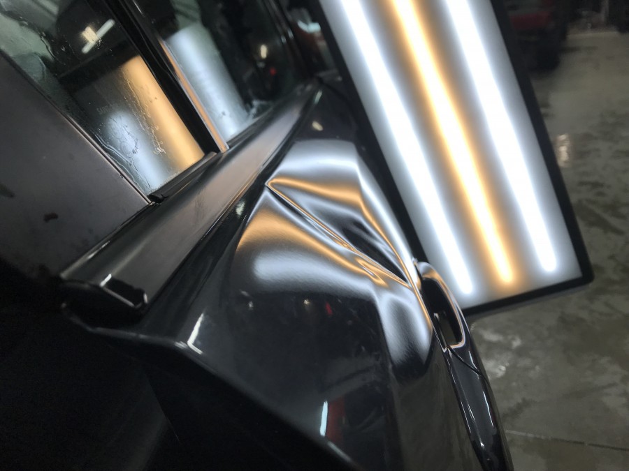 Porte bosselée d'une voiture noire avec néon