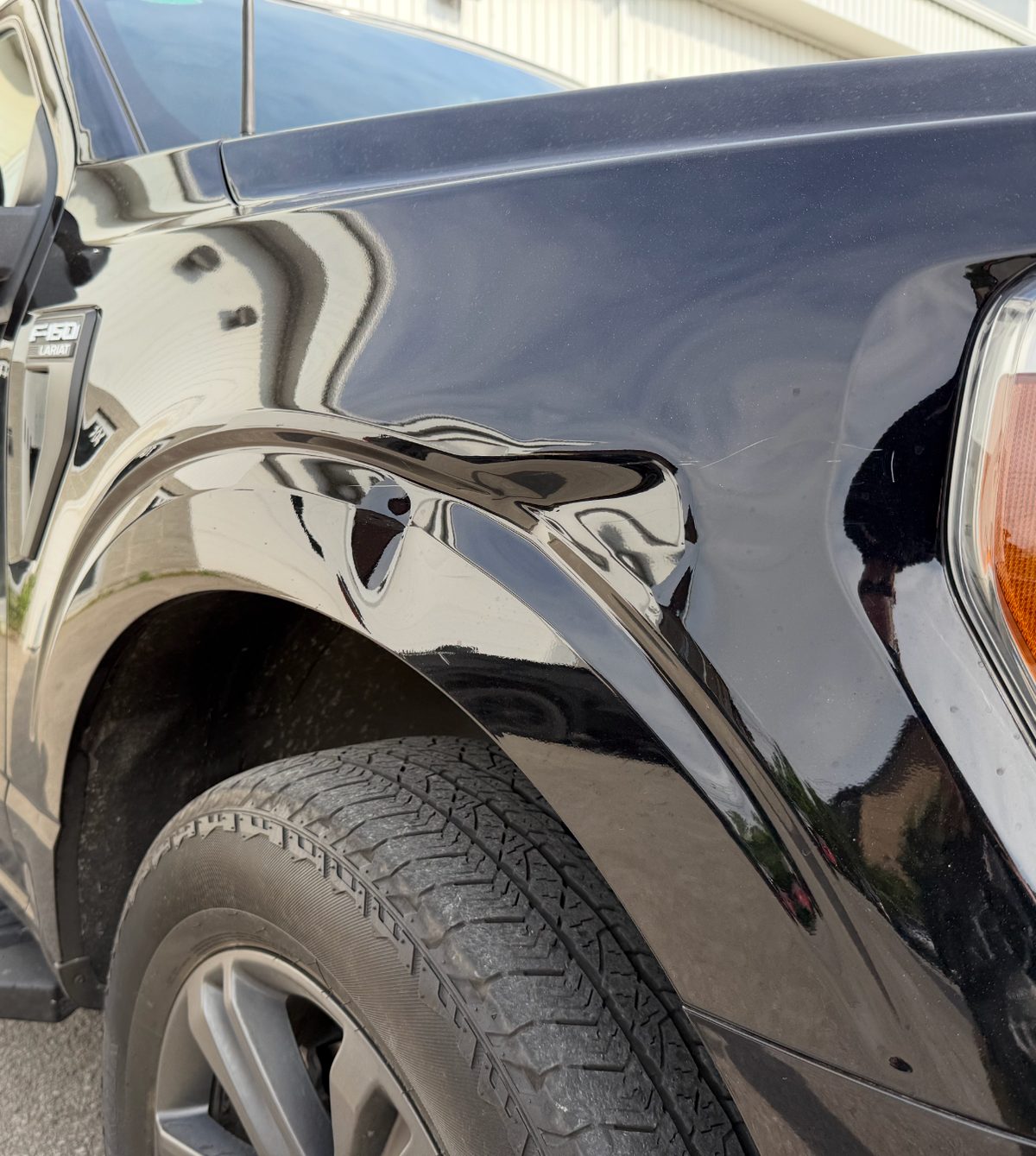 Dented front fender of a black Ford F-150