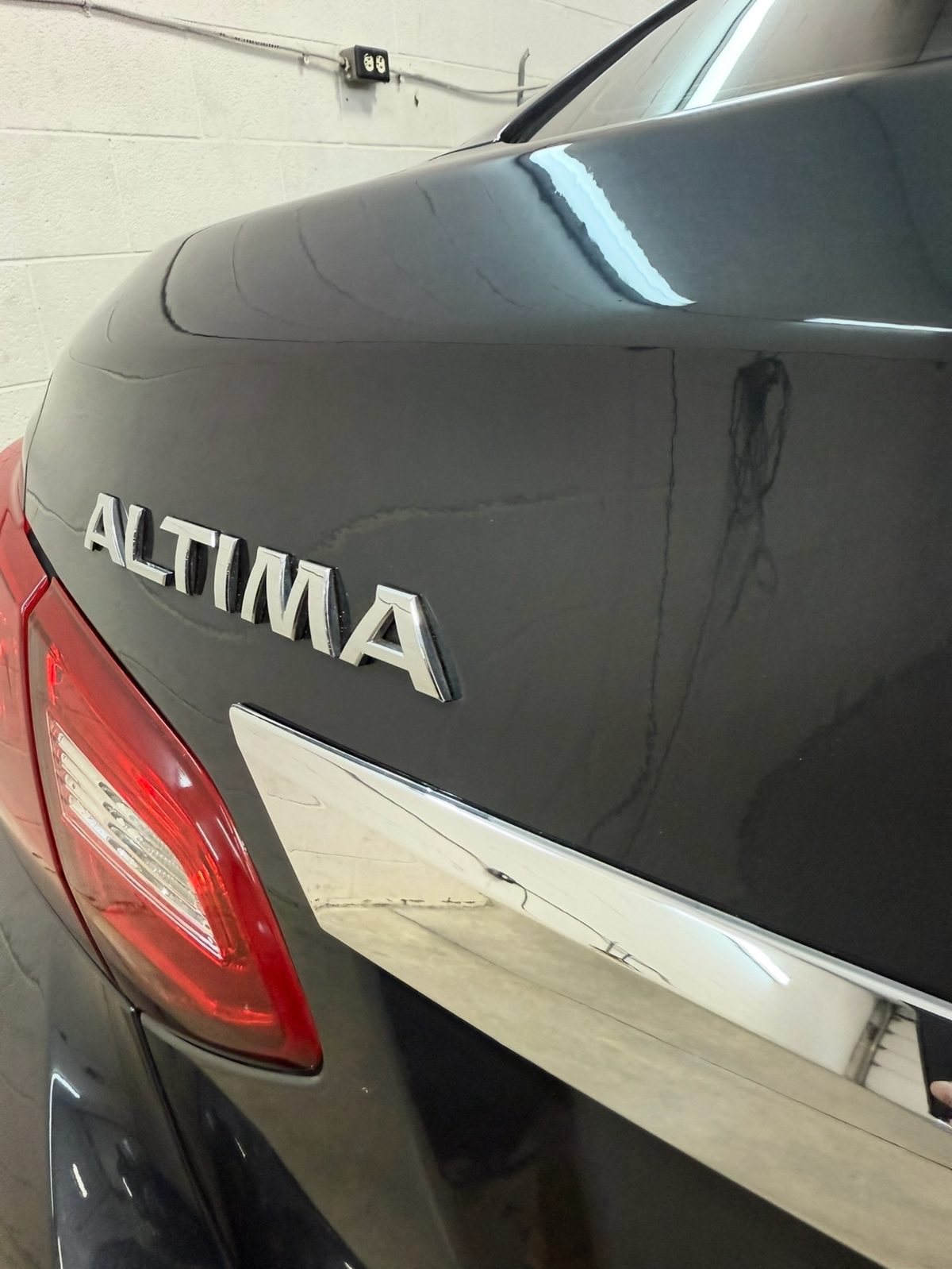 Repaired trunk lid of a black Nissan Altima