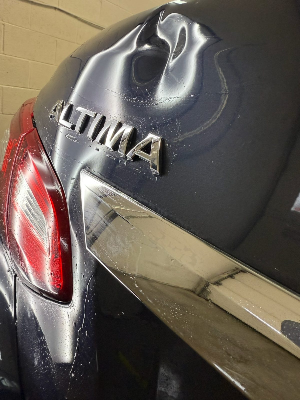 Dented trunk lid of a black Nissan Altima