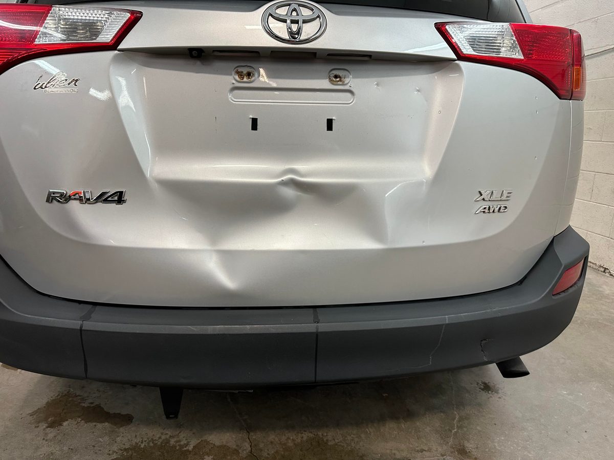 Dented liftgate of a silver Toyota RAV4