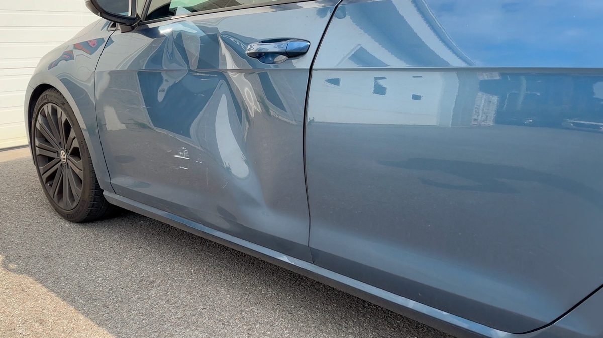 Dented front door of a grey Volkswagen